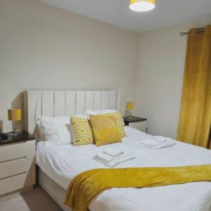 a bedroom with a large white bed with yellow curtains at Remarkable 2-Bed Apartment in Manchester in Manchester