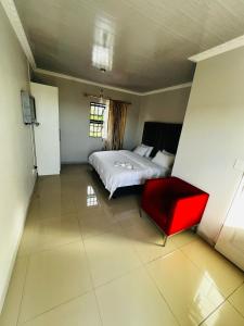 a bedroom with a bed and a red chair at Victoria Guest Lodge in Bellville