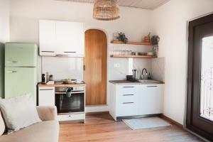 una piccola cucina con armadi bianchi e frigorifero verde di Stellas Village House a Myrtia