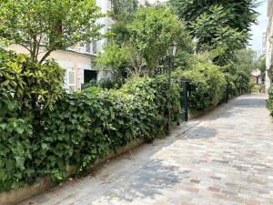 une haie à côté d'une rue avec une clôture dans l'établissement Tour Eiffel - Appartement avec jardin, à Paris