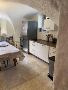 uma cozinha com um frigorífico de aço inoxidável e uma mesa em MAISON CARAIL Névache 14 personnes em Névache