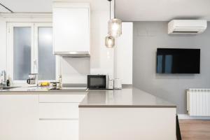 a white kitchen with a sink and a microwave at apartamento exclusivo en velazquez in Madrid