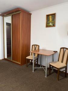 une chambre avec une table, des chaises et une armoire dans l'établissement Viktoria Hotel, à Obroshino