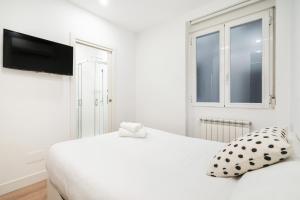 Un dormitorio blanco con una cama blanca y una ventana en apartamento exclusivo en velazquez en Madrid