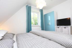 a bedroom with a bed and a flat screen tv at Neu Reet Ferienhaus Svantevit in Lohme