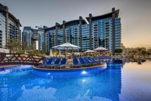 a pool with chairs and umbrellas in front of a hotel at 3BR Oasis on Palm with Sea View, Private beach and Lazy River Access in Dubai
