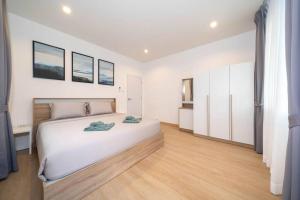 um quarto branco com uma grande cama branca e pisos em madeira em New 2BR townhome 350M walk to kata beach em Praia de Kata