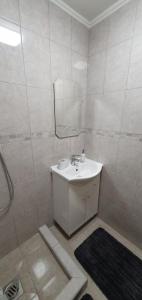 ein weißes Badezimmer mit einem Waschbecken und einem Spiegel in der Unterkunft Tiszavíz Vendégház in Tiszafüred
