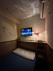 Zimmer mit einem Bett und einem TV an der Wand in der Unterkunft Paris Guesthouse-Tsim Sha Tsui Mansion in Hongkong