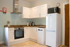 cocina con armarios blancos y nevera en Grisdale View en Penrith