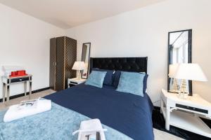 een slaapkamer met een blauw bed met 2 tafels en 2 lampen bij Well Equipped Apartment for Relocators and Contractors in Reading