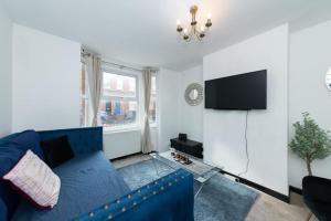een woonkamer met een blauwe bank en een tv bij Well Equipped Apartment for Relocators and Contractors in Reading