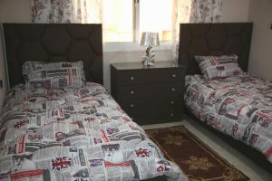 a bedroom with two beds and a bedspread with a newspaper at Appart-ines l'Oasis du confort et luxe in Oujda