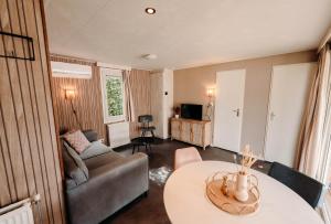 a living room with a couch and a table at Chalet Tulpenweide - recreatie in Breezand