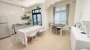 een witte keuken met een tafel en stoelen. bij 春日SpringDay花蓮包棟民宿 in Hualien