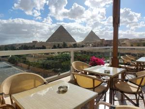 einen Balkon mit Tischen, Stühlen und Pyramiden in der Unterkunft DouDou Pyramids View Hotel in Kairo