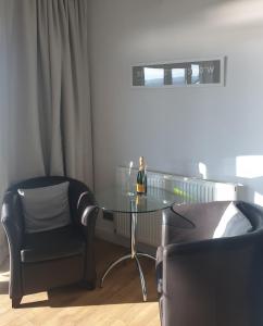 una mesa de cristal y 2 sillas y una botella de vino en The Waters Edge en Lee-on-the-Solent
