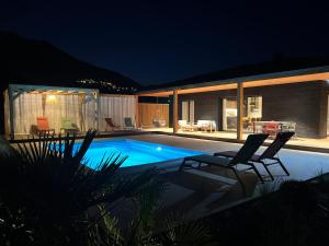 a swimming pool at night with two chairs around it at Villas Vallée d'ASCO in Moltifao