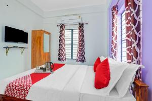a bedroom with a large white bed with red pillows at Hotel O Bevis in Trivandrum