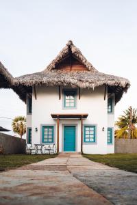 a house with a thatched roof and a blue door at Villa dos Poetas in Barra Grande
