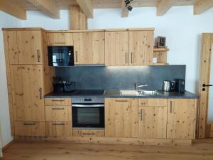 uma cozinha com armários de madeira e um lavatório em Erbhof Fritzing em Ebbs