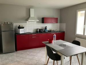 a kitchen with red cabinets and a table with a water bottle at Le 32 in Cognac