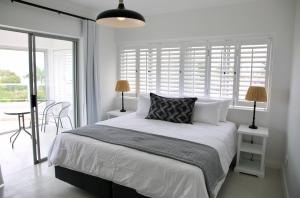 Dormitorio blanco con cama y mesa con sillas en 5 Sun Centre, en Plettenberg Bay