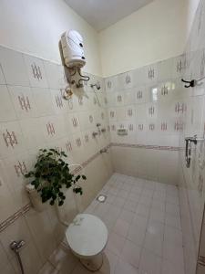 a bathroom with a toilet and a plant in it at Anjunapalms GuestHouse in Anjuna