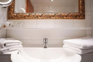 bagno con lavandino, specchio e asciugamani di Hotel Acerina Superior a Lech am Arlberg