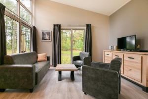 sala de estar con sofá, sillas y TV en Summio Parc De Berkenhorst, en Kootwijk