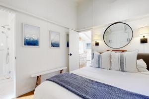 a white bedroom with a large bed and a mirror at Virginia Way Cottage in Laguna Beach