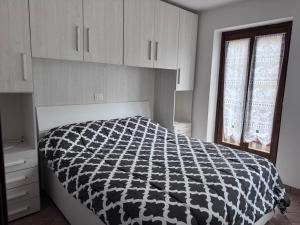 Schlafzimmer mit einem schwarzen und weißen Bett und einem Fenster in der Unterkunft Casa Stefy in Mezzolago