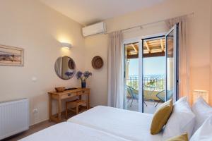 1 dormitorio con cama, escritorio y balcón en Terra Rossa by Konnect, Views to Ionian Sea, en Spartýlas