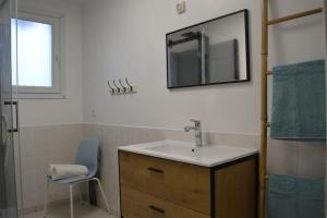 ein Badezimmer mit einem Waschbecken, einem Spiegel und einem Stuhl in der Unterkunft Au calme à la Marelle 