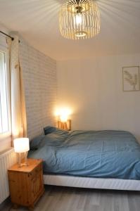 a bedroom with a blue bed and a chandelier at Au calme à la Marelle 