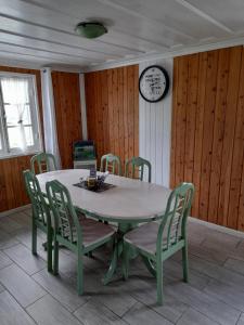 mesa de comedor con sillas y reloj en la pared en Le petit vignoble du brûlé marron, en Cilaos