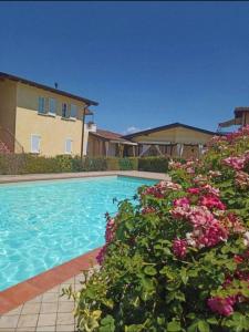 een zwembad met bloemen voor een huis bij Apartment Dragonfly - garden and pool in Manerba del Garda