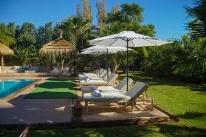 - une rangée de chaises longues et un parasol à côté de la piscine dans l'établissement Villa Atika Maison d'Hôtes & Spa, à Marrakech