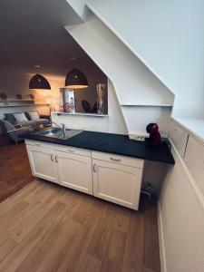 a kitchen with a counter and a sink under a staircase at Logement Romily avec vue Montagne in Le Mont-Dore