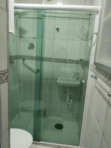 a bathroom with a glass shower with a toilet and a sink at Kitnet Praia Grande in Praia Grande