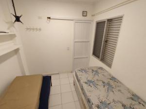 a small bedroom with a bed and a window at Kitnet Praia Grande in Praia Grande