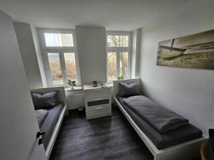 um quarto com duas camas e uma secretária e duas janelas em charmante Ferienwohnung am Stadtwald von Plauen em Plauen