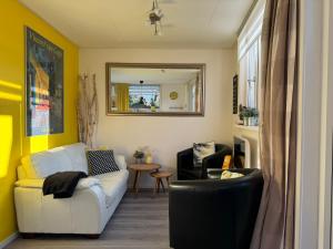 een woonkamer met een witte bank en een spiegel bij Coastal Dreaming in Egmond aan Zee