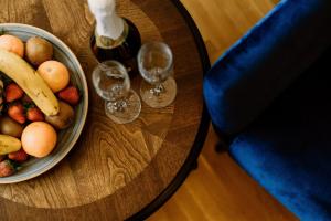 a wooden table with a bowl of fruit and two wine glasses at Korona Pension and Restaurant in Hévíz