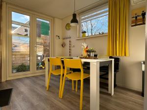 a dining room with a table and yellow chairs at Coastal Dreaming in Egmond aan Zee