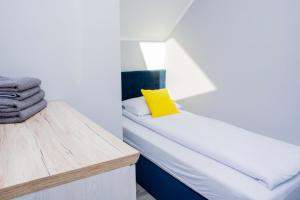 1 dormitorio con 1 cama con almohada amarilla en Apartamenty Cumowa, en Władysławowo