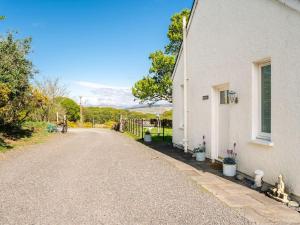 a road next to a white house with plants at Deerside, Tobermory in Tobermory