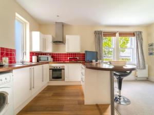 a large kitchen with white cabinets and a table at Deerside, Tobermory in Tobermory