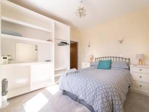 a white bedroom with a bed with blue pillows at Deerside, Tobermory in Tobermory