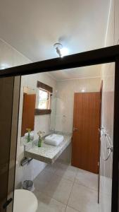 ein Badezimmer mit Waschbecken, Toilette und Spiegel in der Unterkunft Casa do bosque in Conceição da Ibitipoca